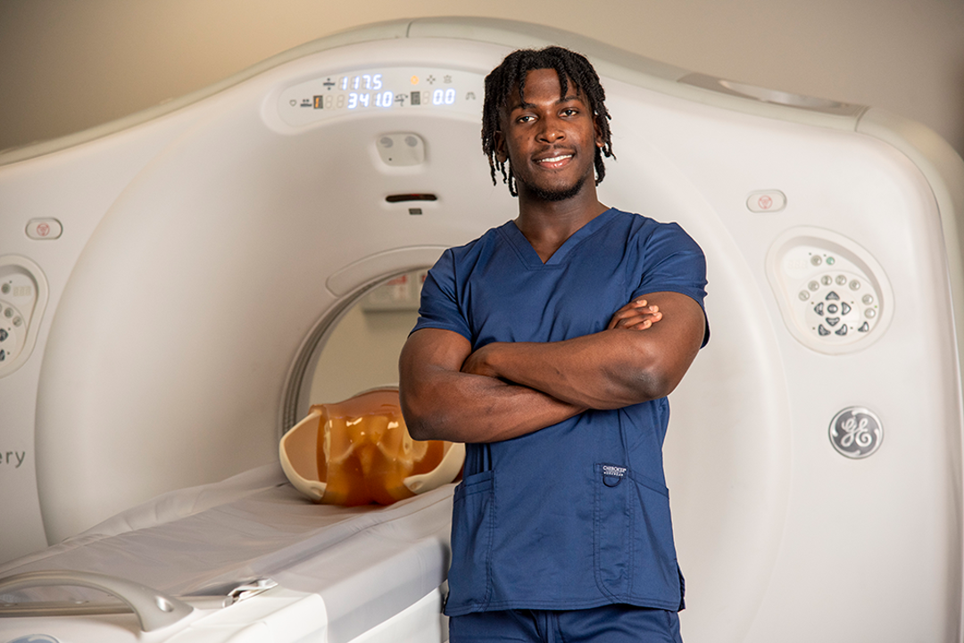 Student standing in front of CT simulator