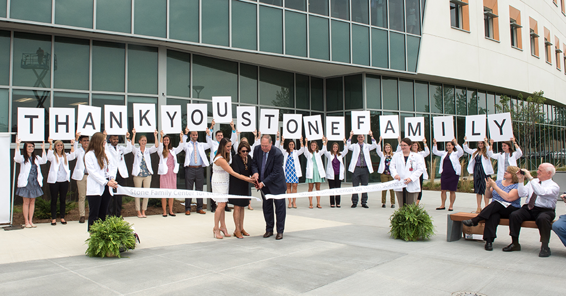 Students holding thank you sign outside the Stone Center during ribbon cutting ceremony
