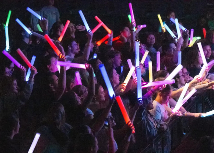 students at a concert holding glow lights in the air
