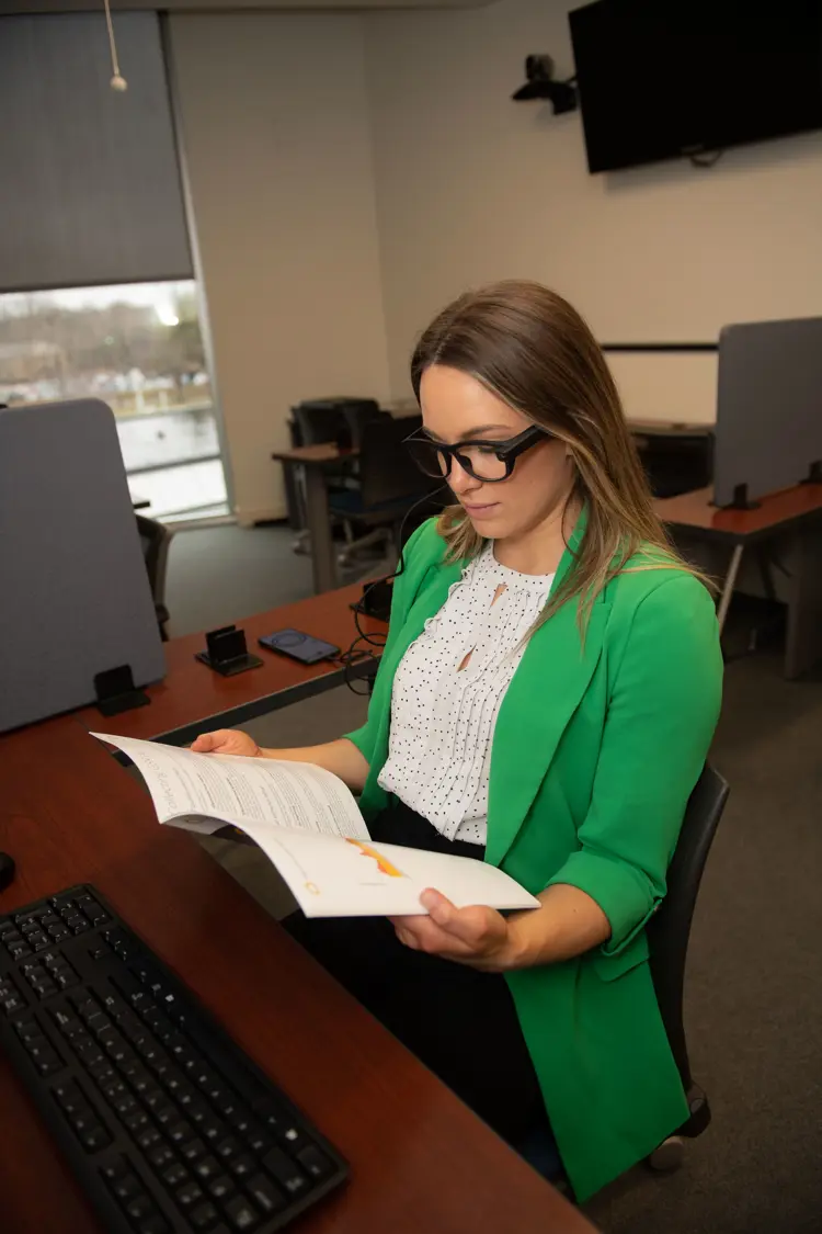 A student participant uses eye tracking glasses to read a book.