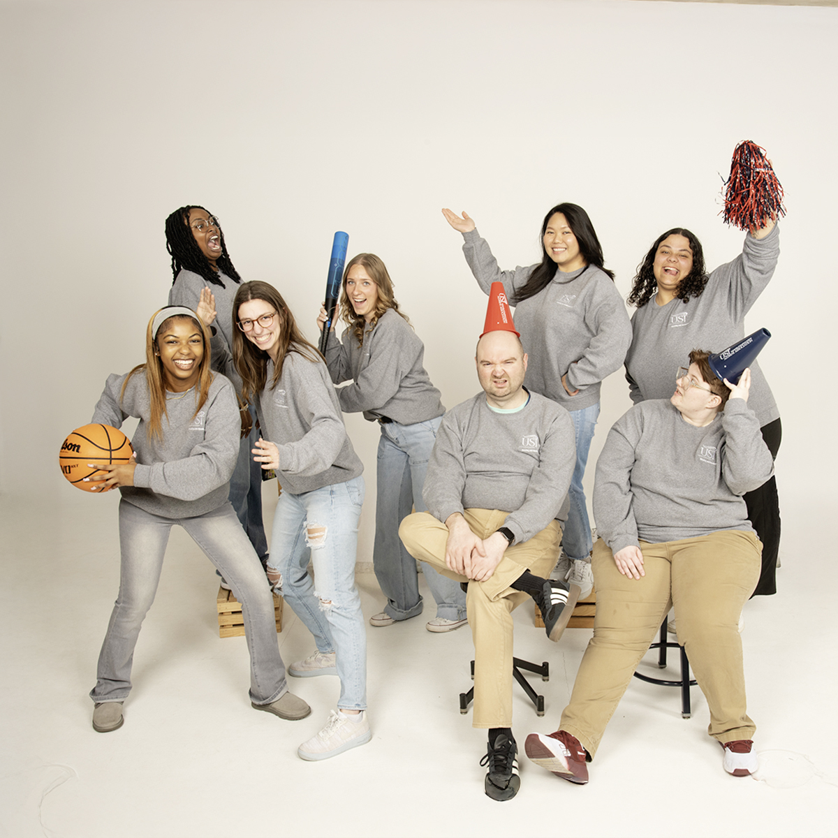 Area Coordinators play with athletic props and make silly in the photo studio for their informal group photo.