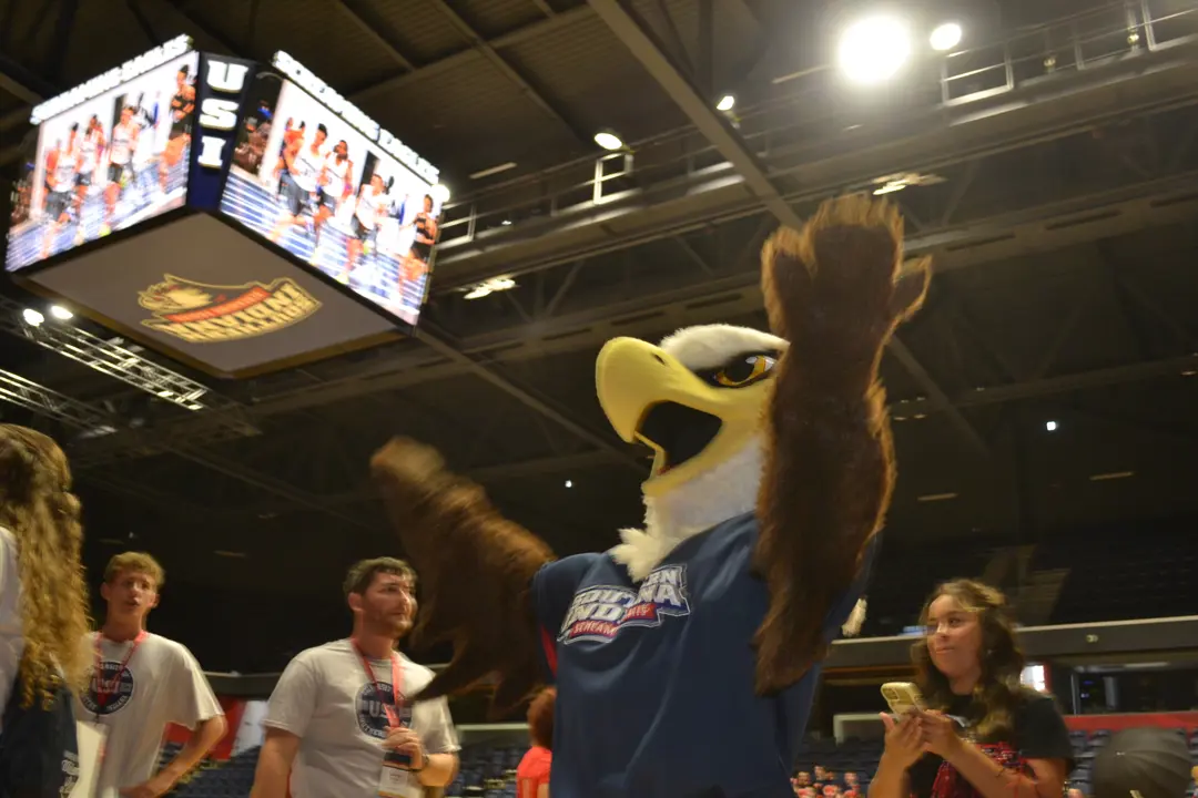 Archie raises his hands in celebration in front of the jumbotron in Liberty Arena